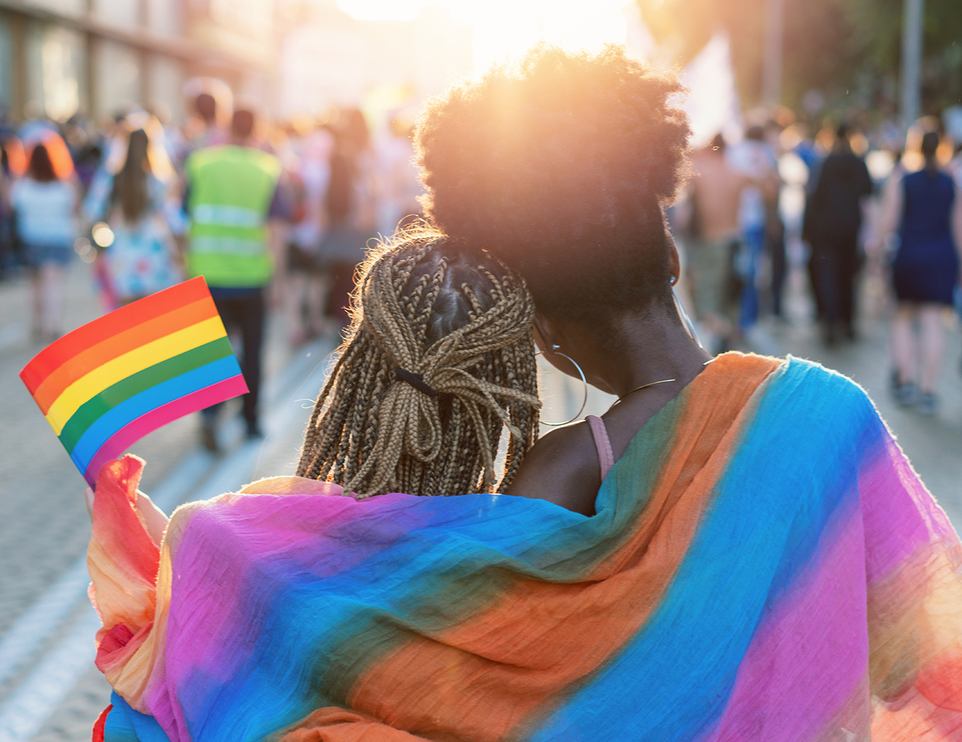 Couple watching a sunset with a pride flag around their shoulders